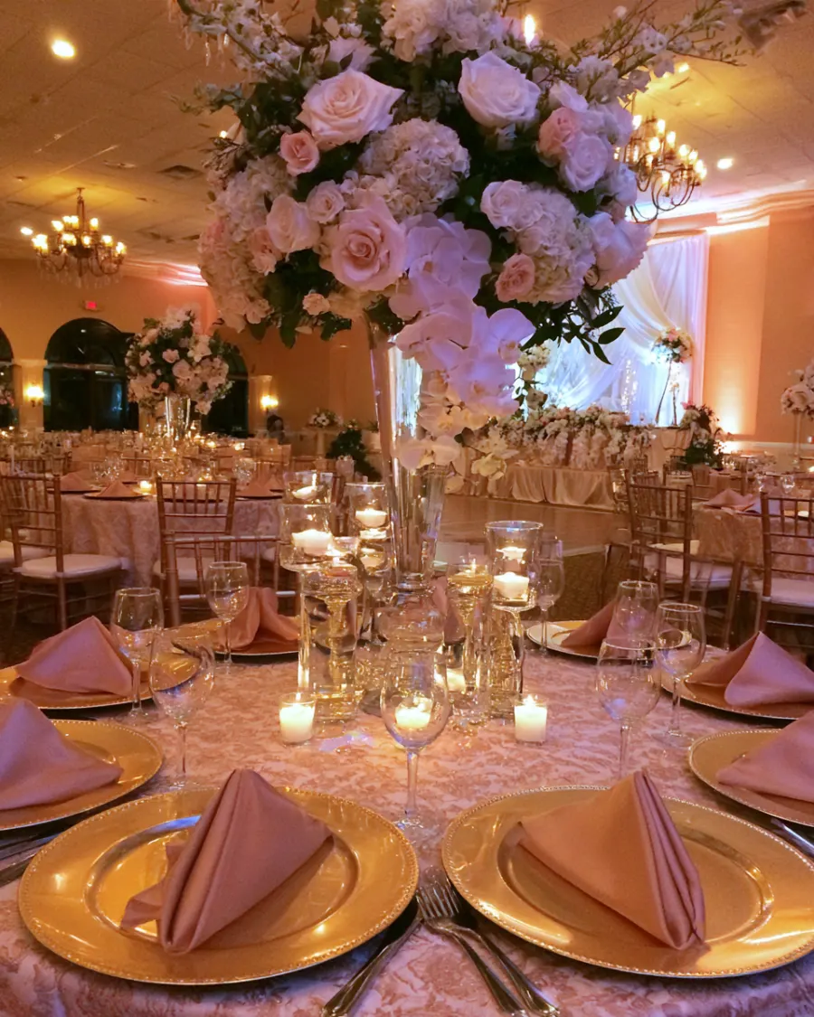 A styled round table with a tall flower centerpiece and gold chargers