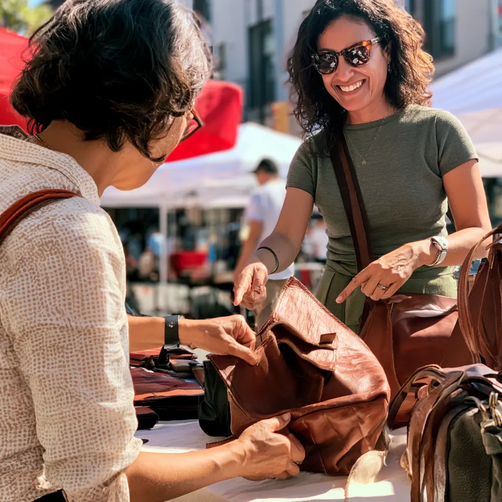 Marisol showing a customer the stitching on a bag
