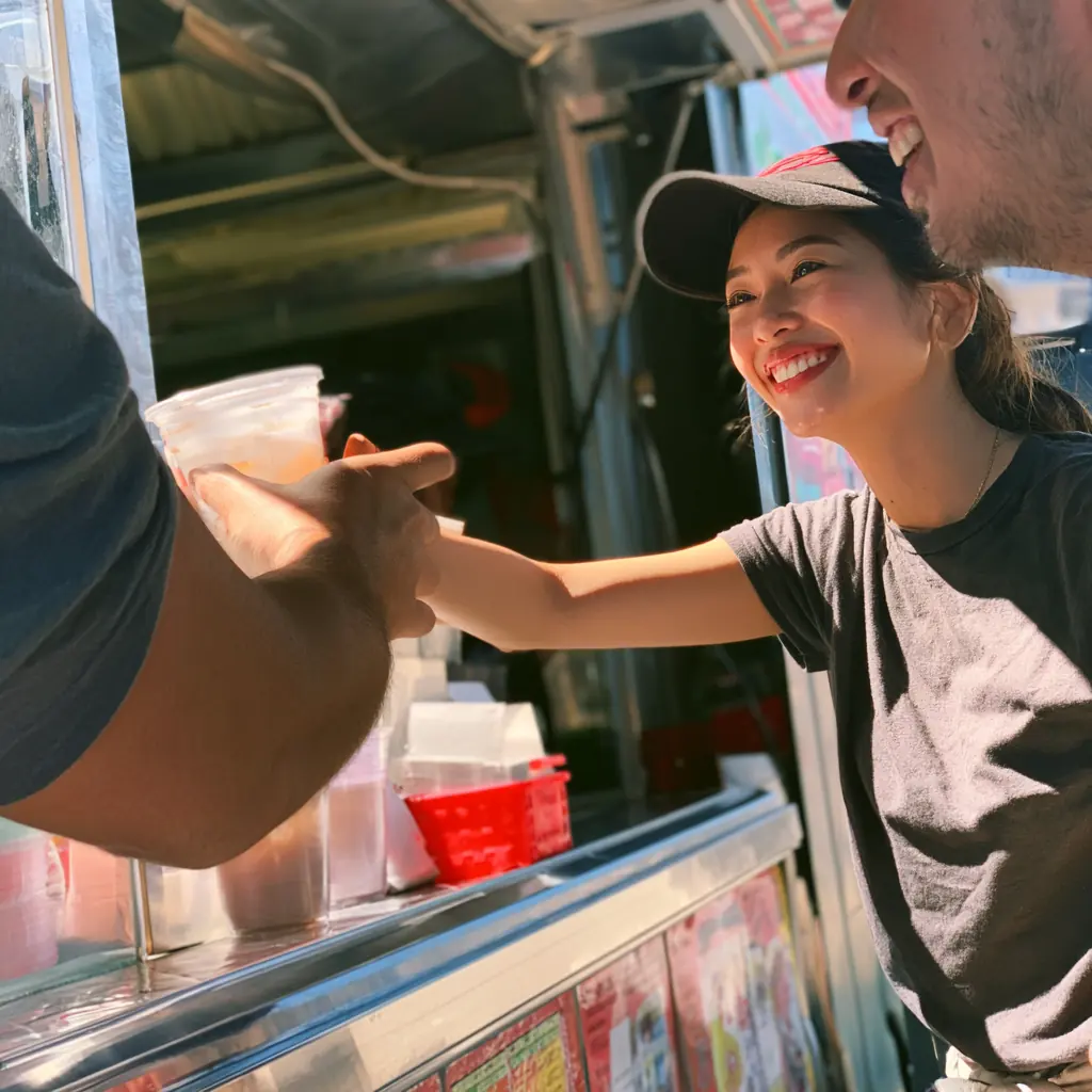 Vy handing a drink to a customer through the stand window